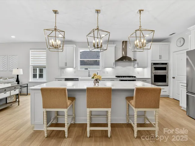 a kitchen with stainless steel appliances granite countertop a dining table chairs and white cabinets