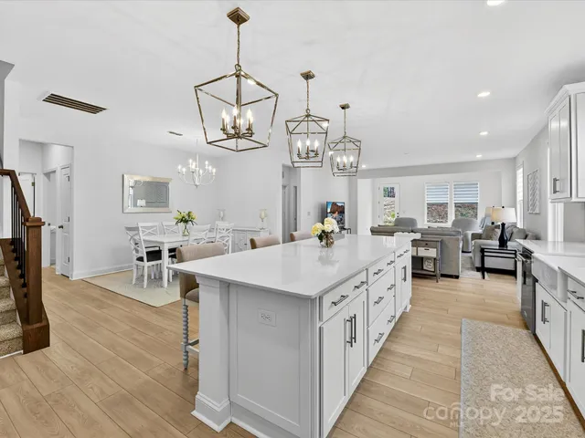 a large white kitchen with sink a counter top space and stainless steel appliances