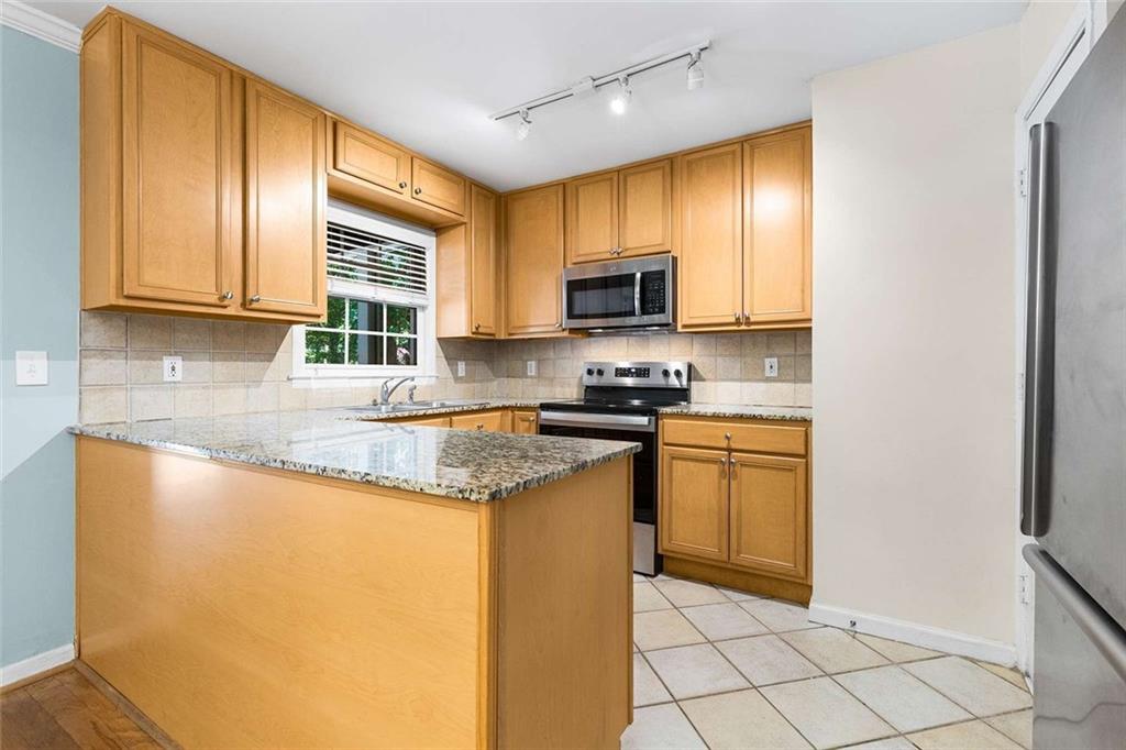 1101 Collier Road Northwest, Unit P2 Atlanta, GA 30318 - Photo 8 of 26 a kitchen with stainless steel appliances granite countertop a stove a sink and a microwave
