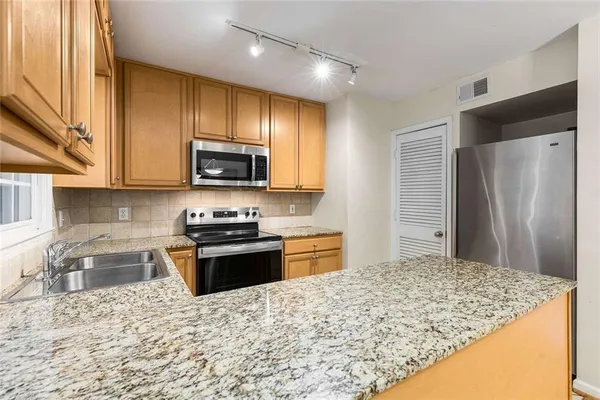 a kitchen with stainless steel appliances granite countertop a stove top oven a refrigerator and a sink
