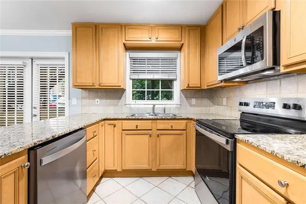 a kitchen with granite countertop cabinets stainless steel appliances a sink and a window