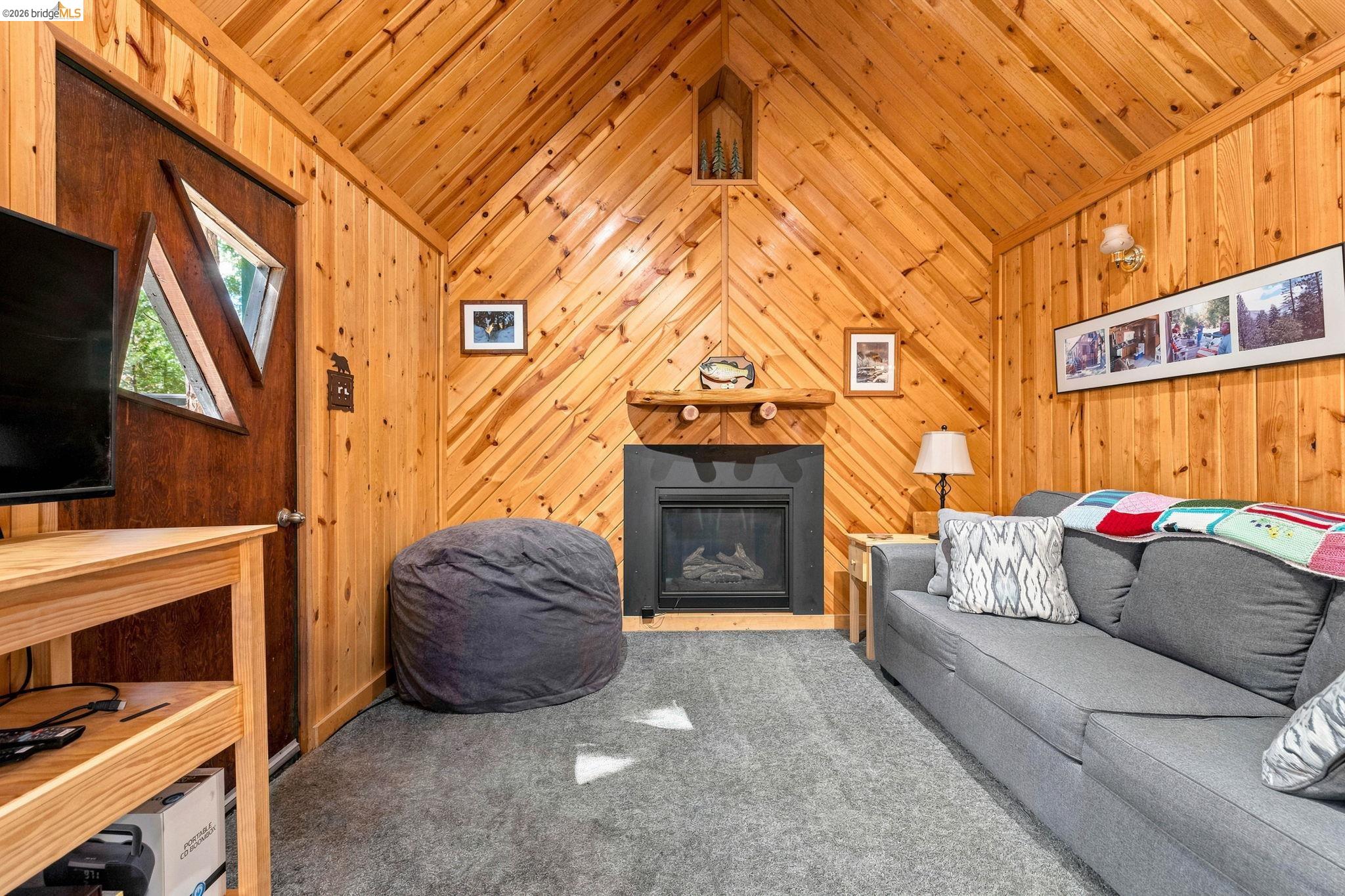 26457 Crystal Road Long Barn, CA 95335 - Photo 9 of 39 Living area featuring extensive natural wood paneling throughout, a vaulted ceiling, and gray carpeting