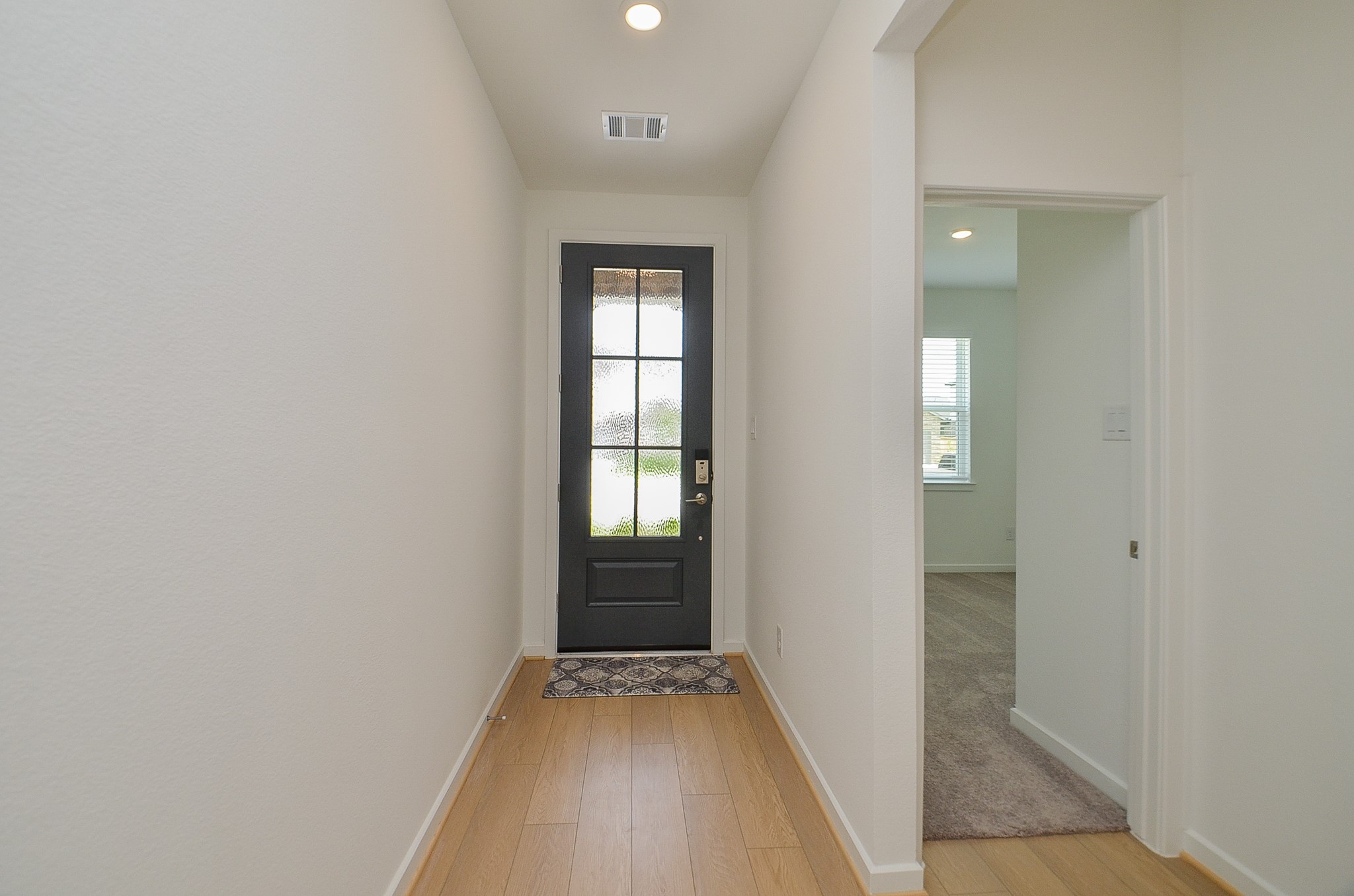 9727 Rialto Hts Drive Cypress, TX 77433 - Photo 5 of 37 Bright entryway featuring a modern black front door with glass panels, light flooring, and an adjacent room with carpet visible through an open doorway.