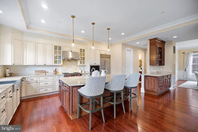 a large kitchen with kitchen island granite countertop lots of white cabinets appliances and dining table