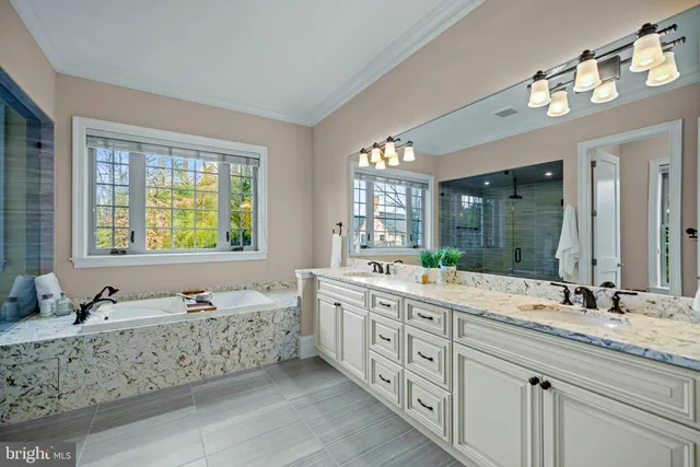 a bathroom with a granite countertop double vanity sink a large mirror and a bathtub