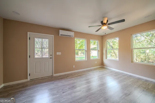 a view of an empty room with wooden floor and a window