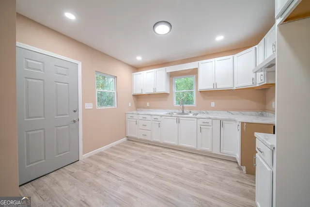 a kitchen with white cabinets and sink
