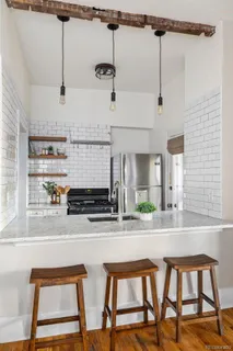a kitchen with stainless steel appliances kitchen island a table chairs in it and wooden floors