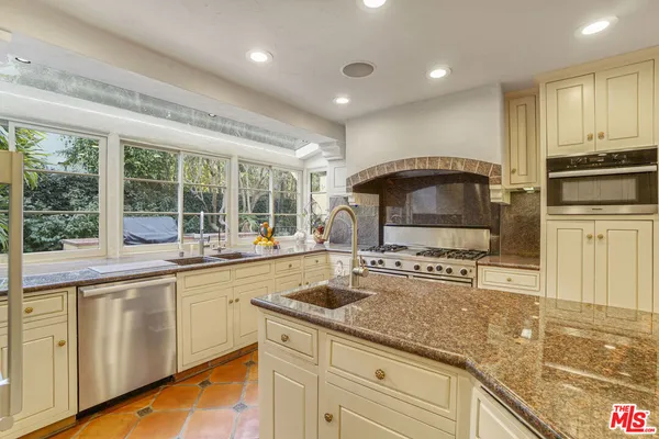 a kitchen with stainless steel appliances granite countertop a sink stove and cabinets