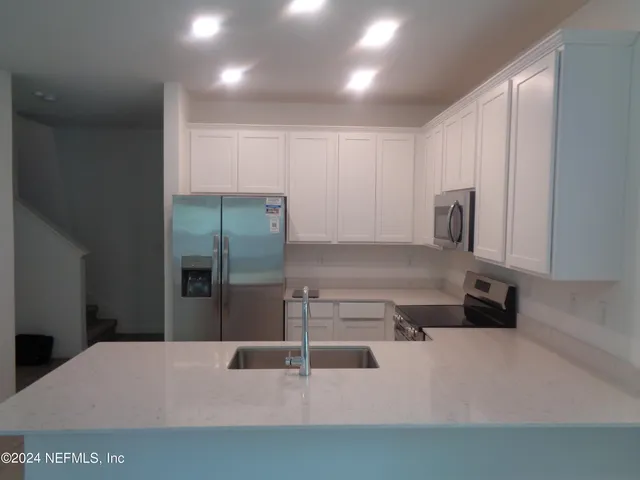 a kitchen with stainless steel appliances kitchen island a refrigerator sink and stove