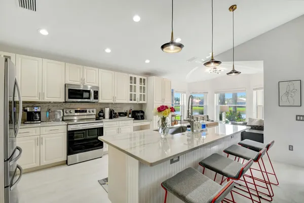a kitchen with stainless steel appliances granite countertop a stove top oven a sink a stove a dining table and chairs with white cabinets