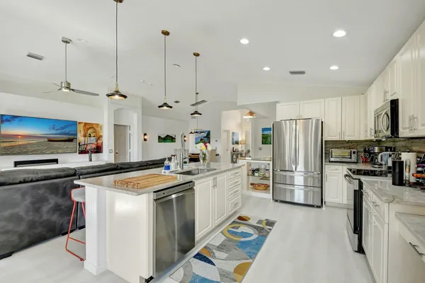a kitchen with refrigerator a stove a sink dishwasher a oven with white cabinets and wooden floor