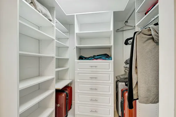 a view of walk in closet with clothes and shoes