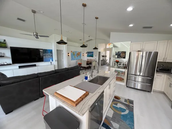 a kitchen with stainless steel appliances a stove a refrigerator a sink a dining table and chairs