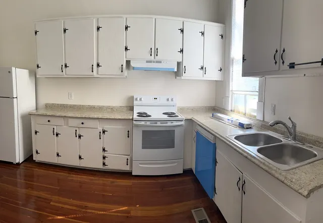 a kitchen with granite countertop a sink a stove and cabinets
