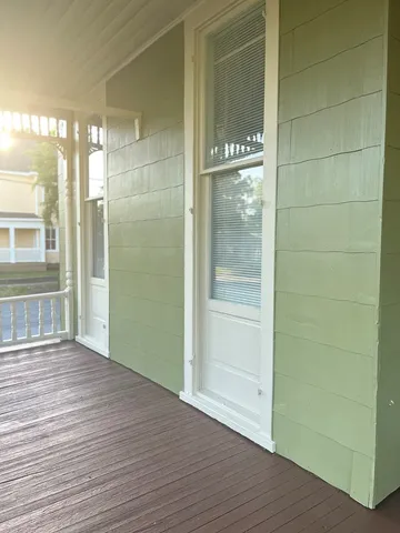 a view of an empty room with wooden floor and a bathroom