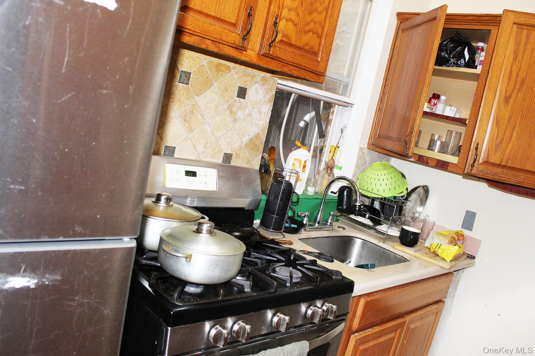 1731 White Plains Road Bronx, NY 10462 - Photo 13 of 16 Kitchen with fridge, stainless steel gas stove, brown cabinets, and light countertops