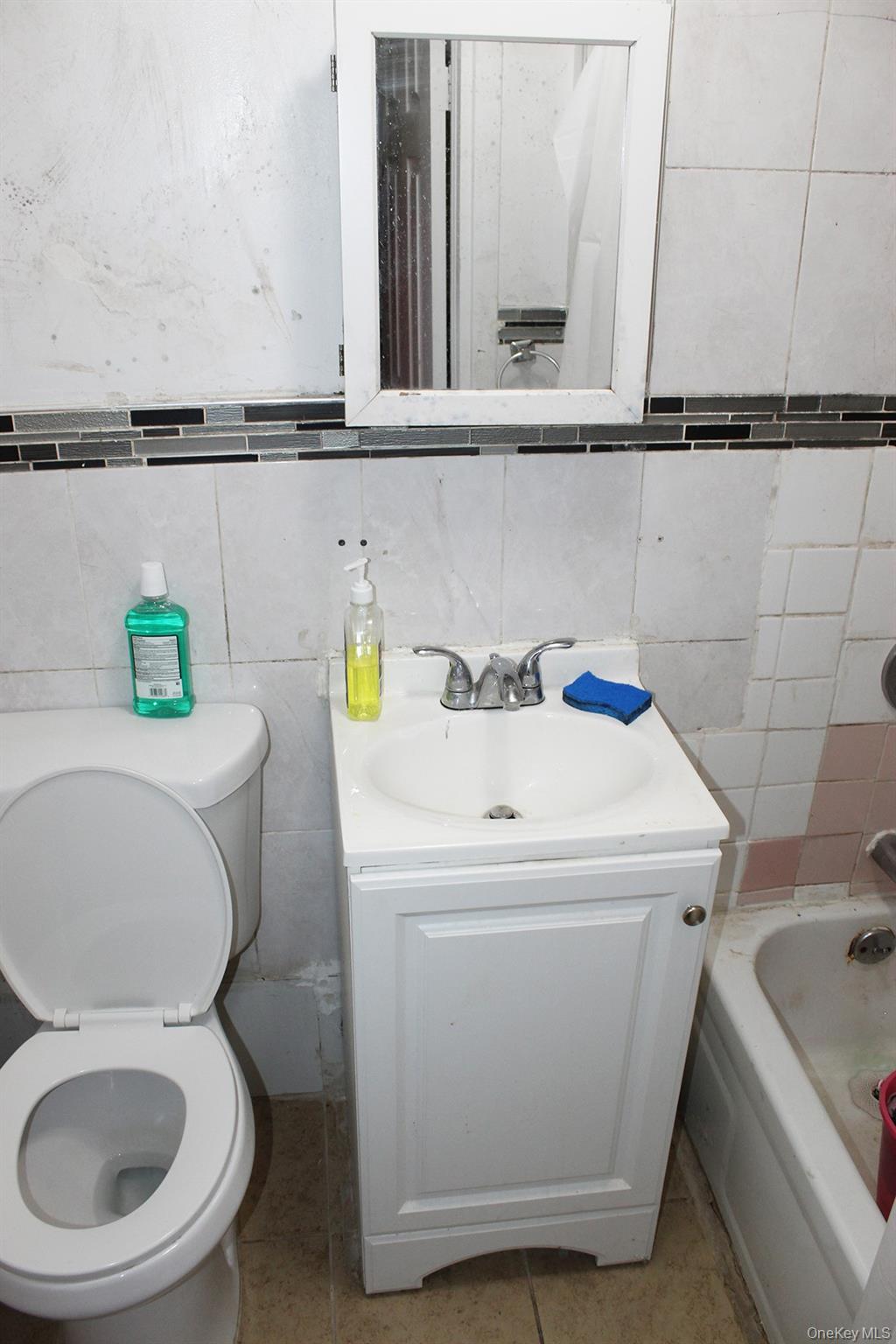 1731 White Plains Road Bronx, NY 10462 - Photo 14 of 16 Full bathroom featuring tile walls, vanity, tile patterned flooring, a bathtub, and tasteful backsplash