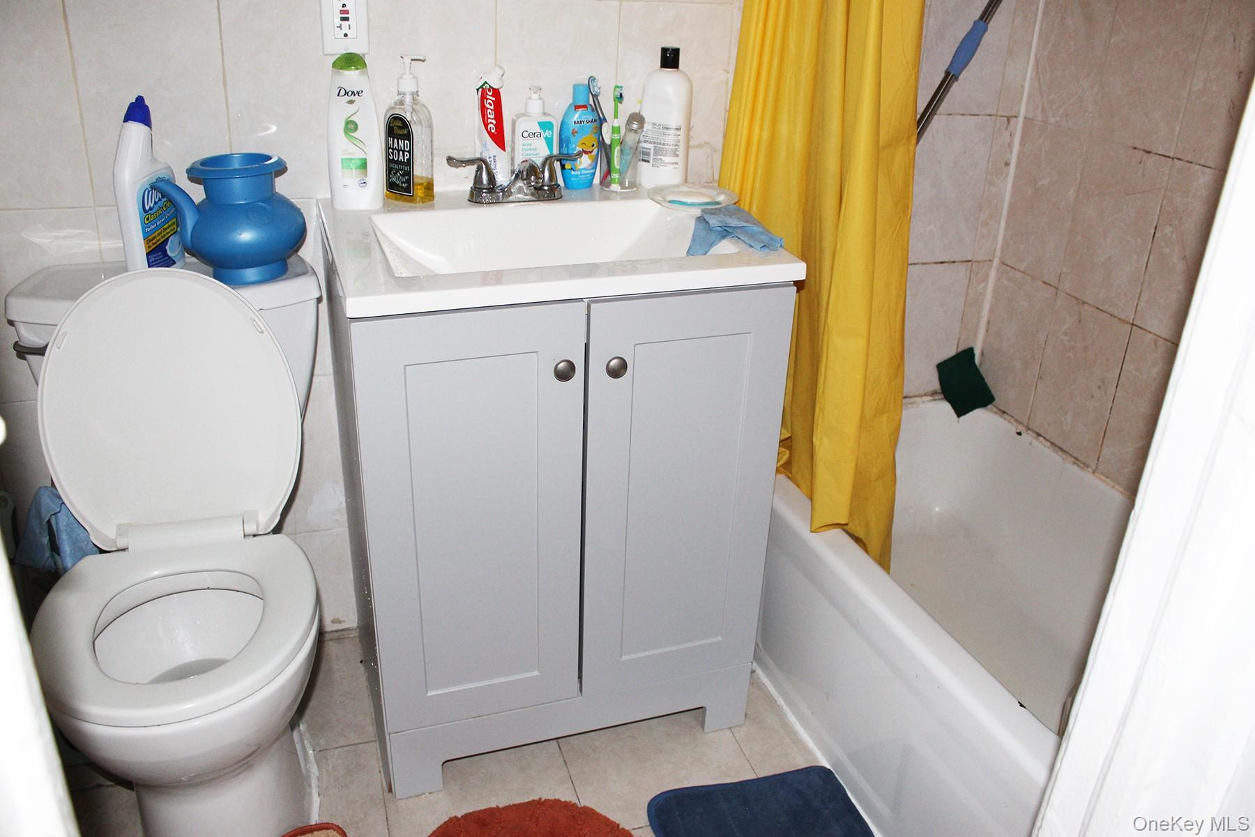 1731 White Plains Road Bronx, NY 10462 - Photo 4 of 16 Bathroom featuring tile patterned flooring, shower / bath combo with shower curtain, vanity, and tile walls