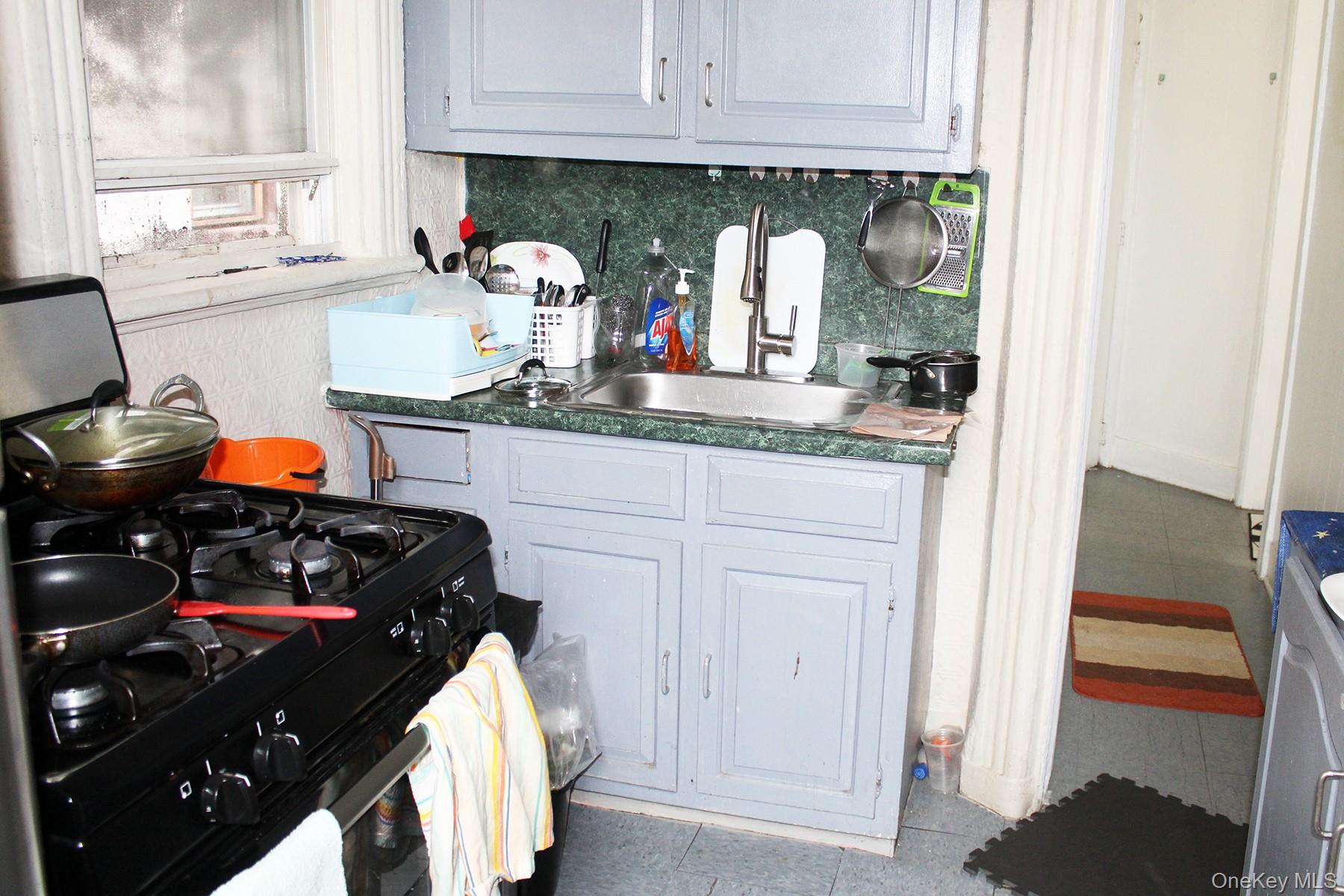 1731 White Plains Road Bronx, NY 10462 - Photo 6 of 16 Kitchen featuring black gas stove, white cabinets, backsplash, tile patterned flooring, and washer / clothes dryer