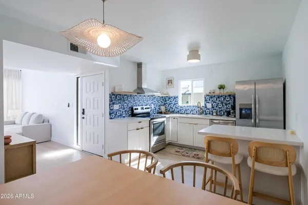 a kitchen with white cabinets and chairs