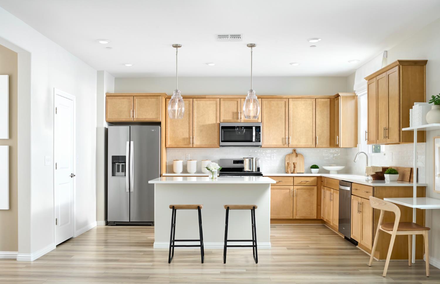 a kitchen with stainless steel appliances granite countertop a sink a stove a refrigerator cabinets and a dining table with wooden floor