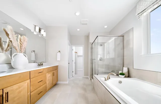 a bathroom with a tub sink double vanity and mirrors