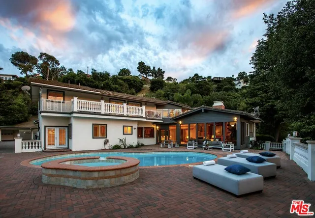 a front view of a house with garden and trees