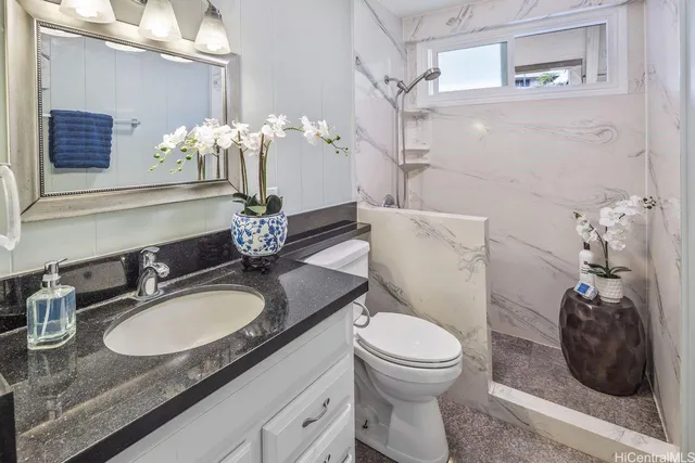 a bathroom with a granite countertop toilet a sink and a mirror