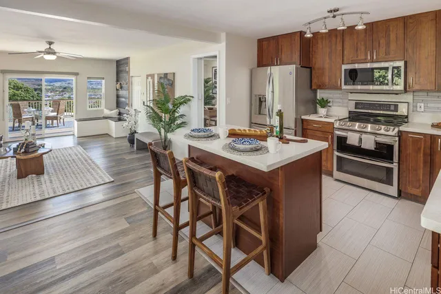 a kitchen with stainless steel appliances kitchen island granite countertop a stove refrigerator and microwave