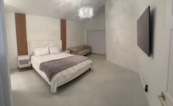 a bedroom with a bed flat screen tv and a chandelier