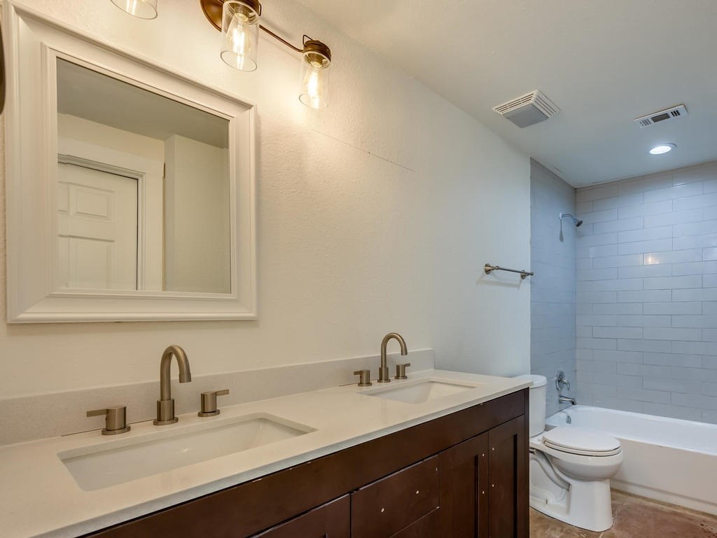 110 South Main Street, Unit 104 Elgin, TX 78621 - Photo 10 of 19 a bathroom with a toilet a sink a mirror and bathtub