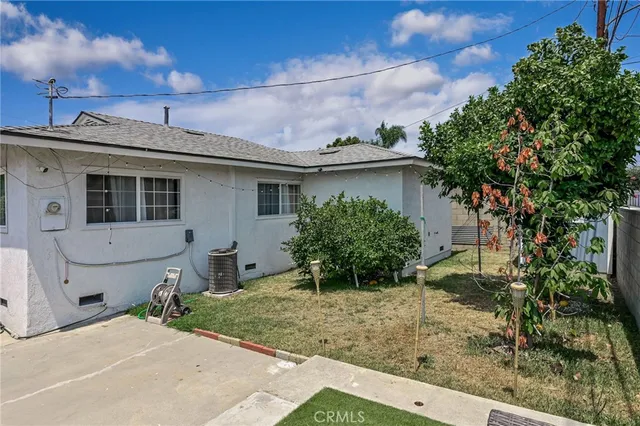 a backyard of a house with potted plants and large tree