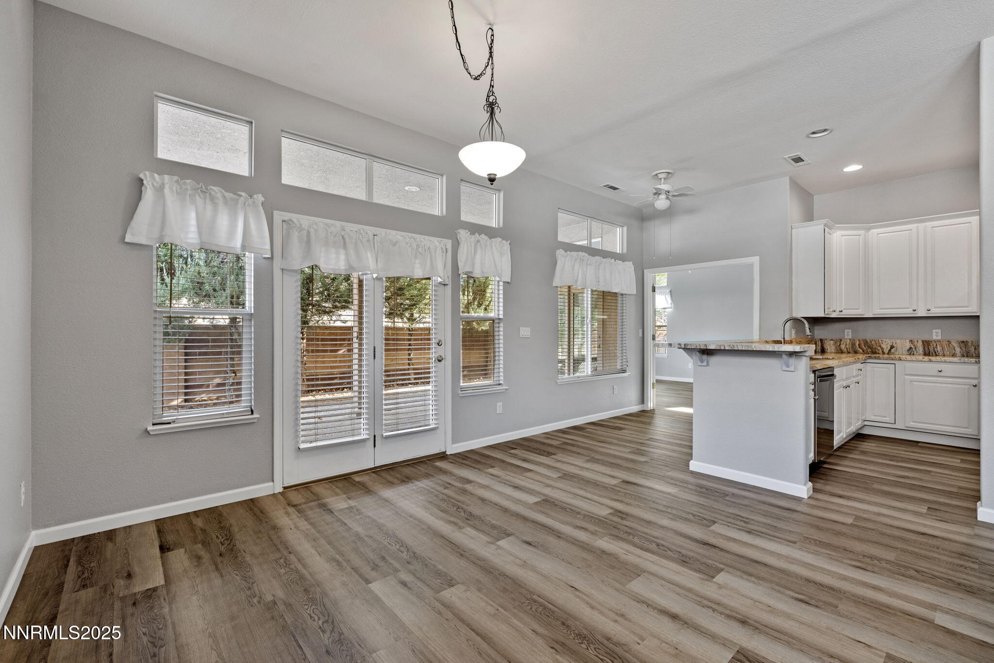 412 Sierra Leaf Circle Reno, NV 89511 - Photo 13 of 36 a view of an empty room with wooden floor and a kitchen