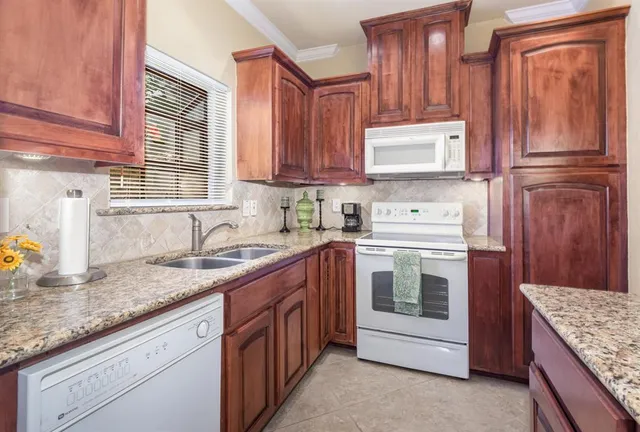 a kitchen with granite countertop stainless steel appliances a sink stove and cabinets