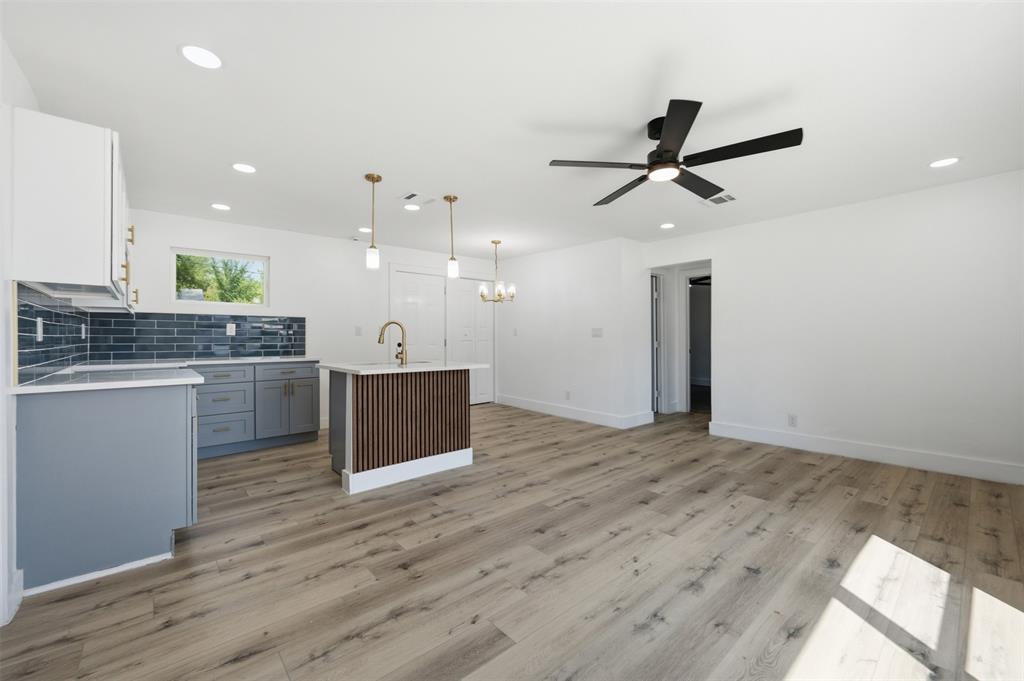 905 East Shaw Street Fort Worth, TX 76110 - Photo 8 of 19 Kitchen island with fluted paneling, wood-finish flooring, recessed lighting, ceiling fan, and subway tile backsplash