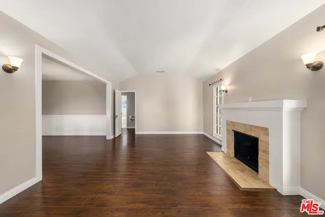a view of an empty room with wooden floor fireplace and a window