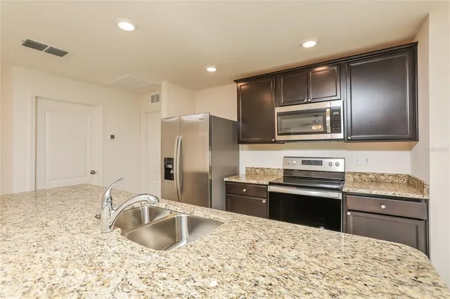 a kitchen with stainless steel appliances granite countertop a sink stove and refrigerator