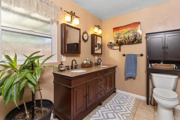 a bathroom with a granite countertop sink a toilet and mirror