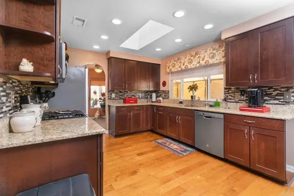 a kitchen with kitchen island granite countertop a sink cabinets and stainless steel appliances