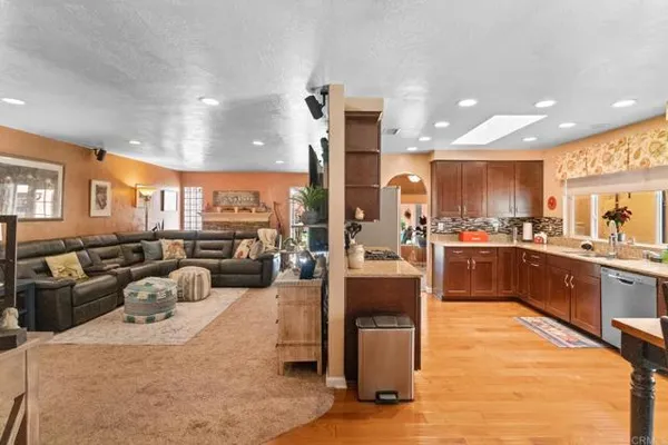 a large kitchen with stainless steel appliances kitchen island a large counter top and a view of living room