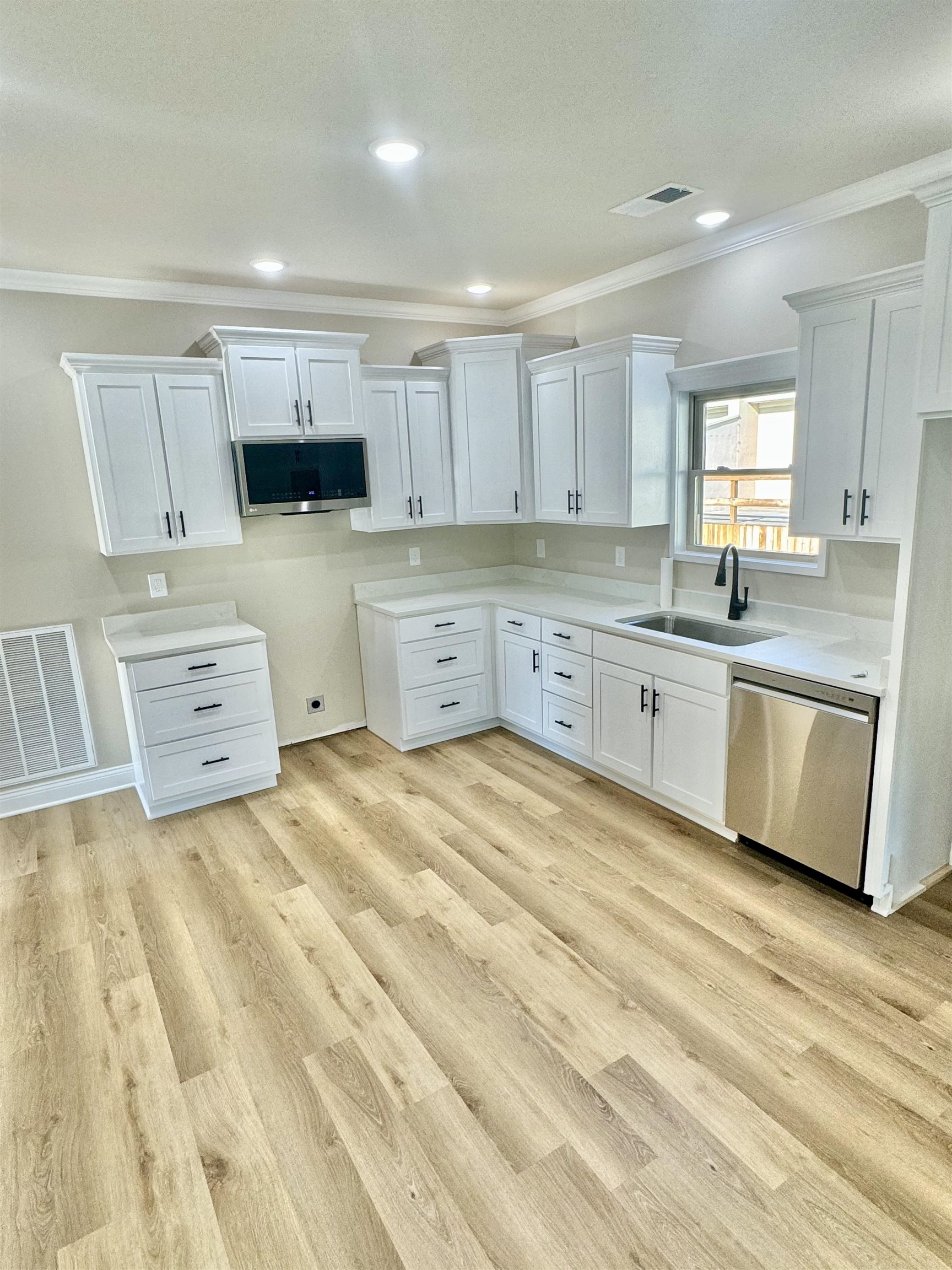 210 Church Street Ripley, TN 38063 - Photo 4 of 14 Kitchen featuring light hardwood / wood-style floors, white cabinetry, crown molding, and stainless steel appliances