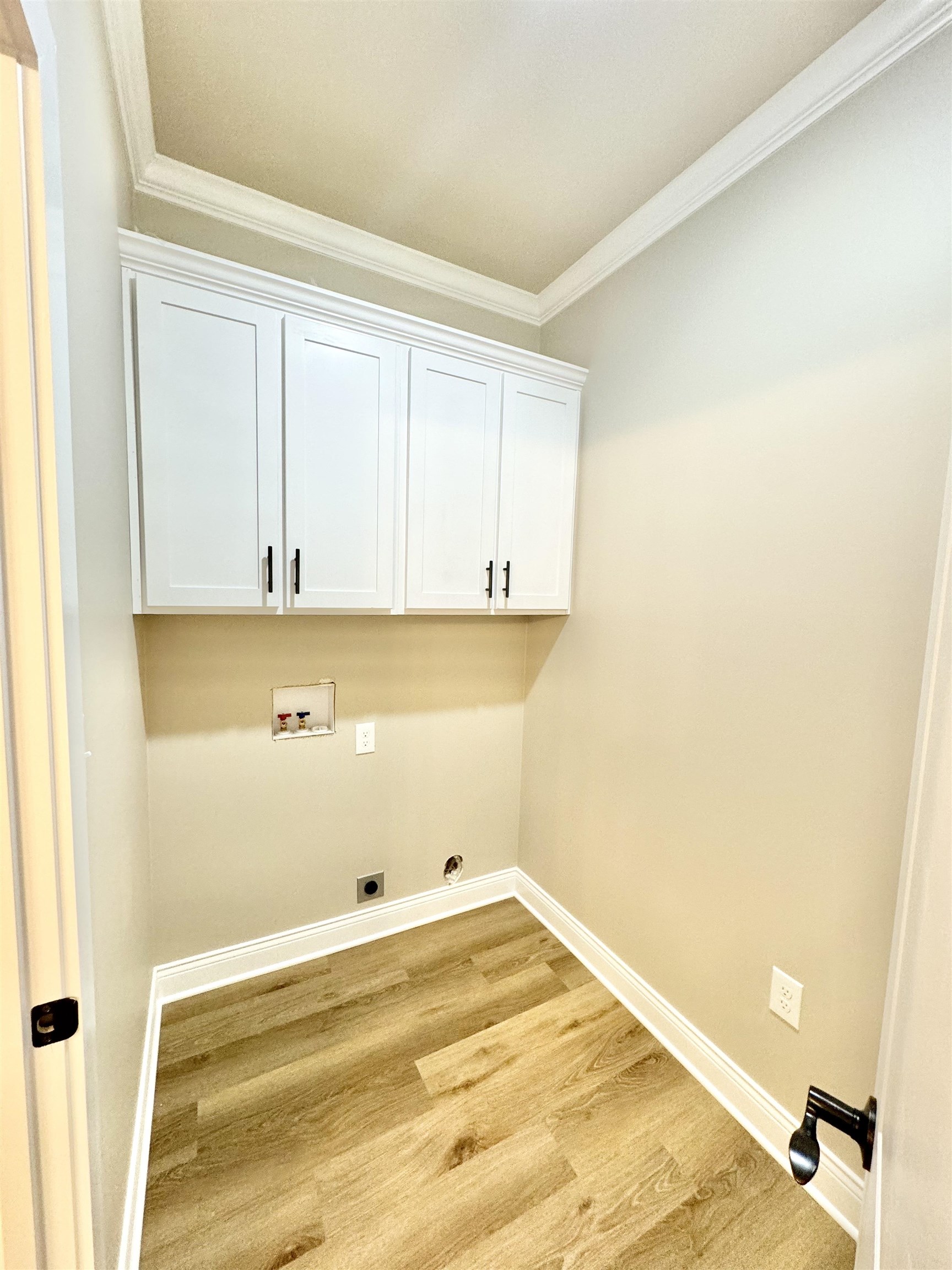 210 Church Street Ripley, TN 38063 - Photo 10 of 14 Laundry area featuring cabinets, electric dryer hookup, ornamental molding, light wood-type flooring, and hookup for a washing machine
