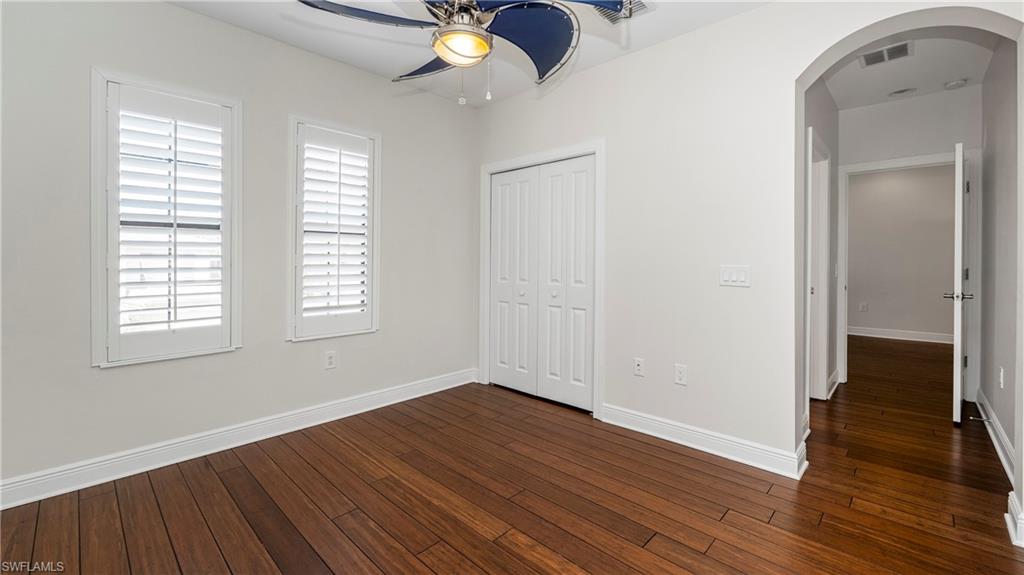 1238 Kendari Terrace Naples, FL 34113 - Photo 27 of 50 Unfurnished bedroom featuring arched walkways, dark wood-type flooring, a ceiling fan, and a closet