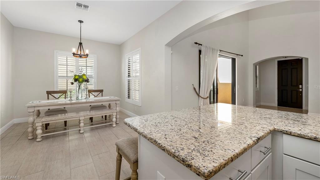 1238 Kendari Terrace Naples, FL 34113 - Photo 5 of 50 Kitchen featuring white cabinets, light stone counters, arched walkways, and a kitchen bar