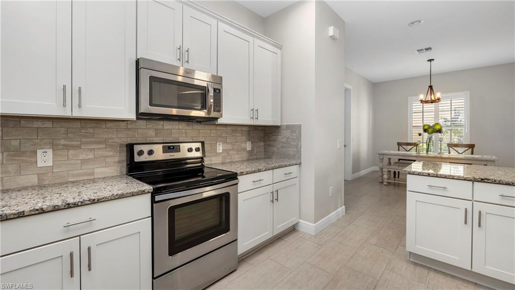 1238 Kendari Terrace Naples, FL 34113 - Photo 7 of 50 Kitchen with stainless steel appliances, white cabinetry, light stone countertops, and decorative backsplash