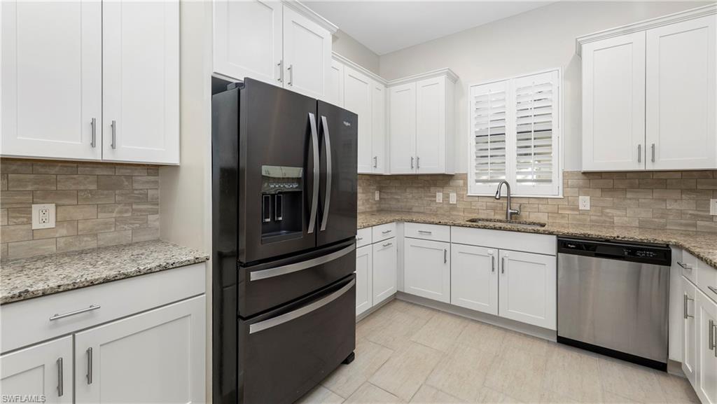 1238 Kendari Terrace Naples, FL 34113 - Photo 9 of 50 Kitchen with black fridge with ice dispenser, white cabinets, dishwasher, and light stone countertops