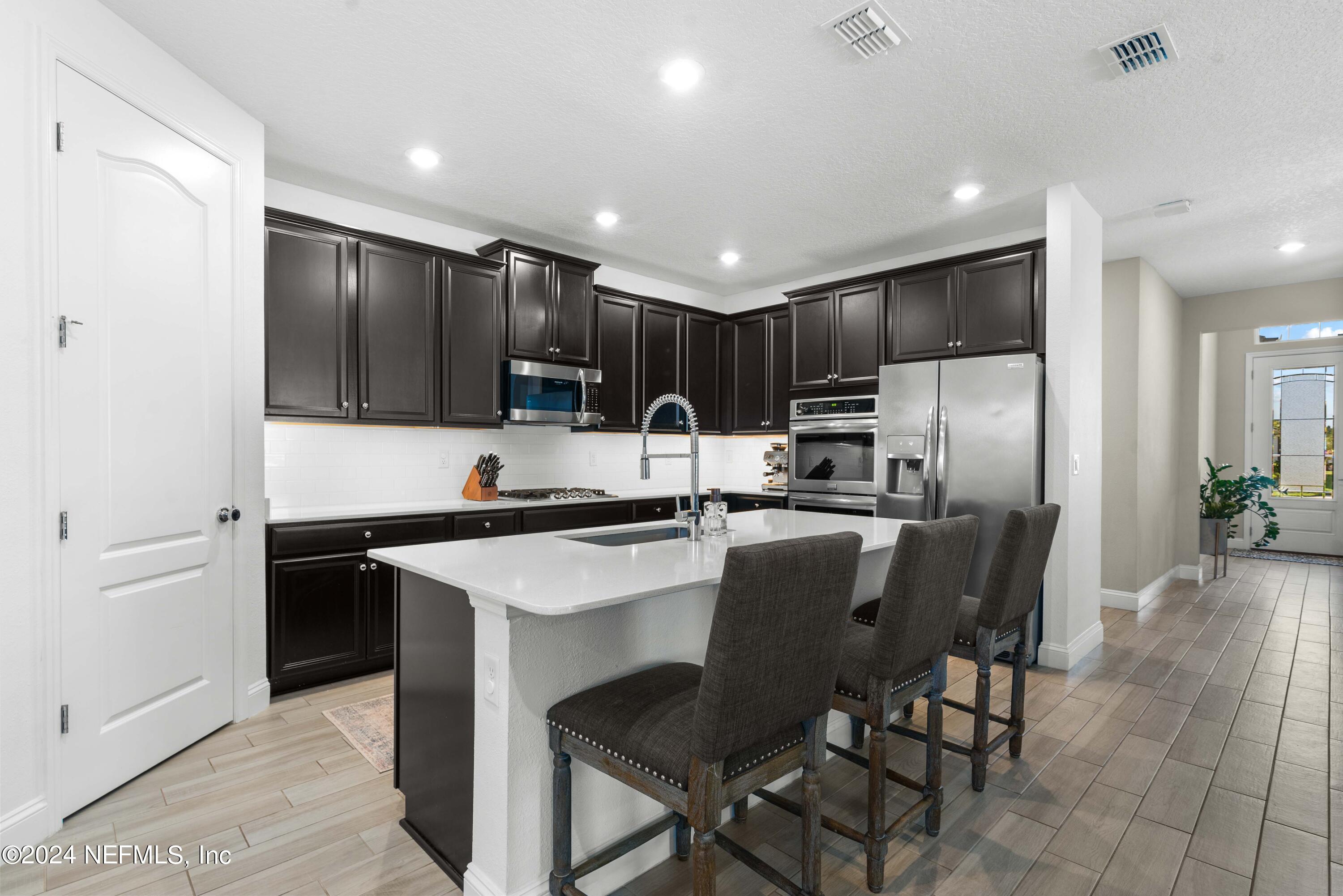 2672 Alexia Circle Jacksonville, FL 32246 - Photo 4 of 33 a kitchen with stainless steel appliances kitchen island granite countertop a sink a stove a refrigerator and cabinets