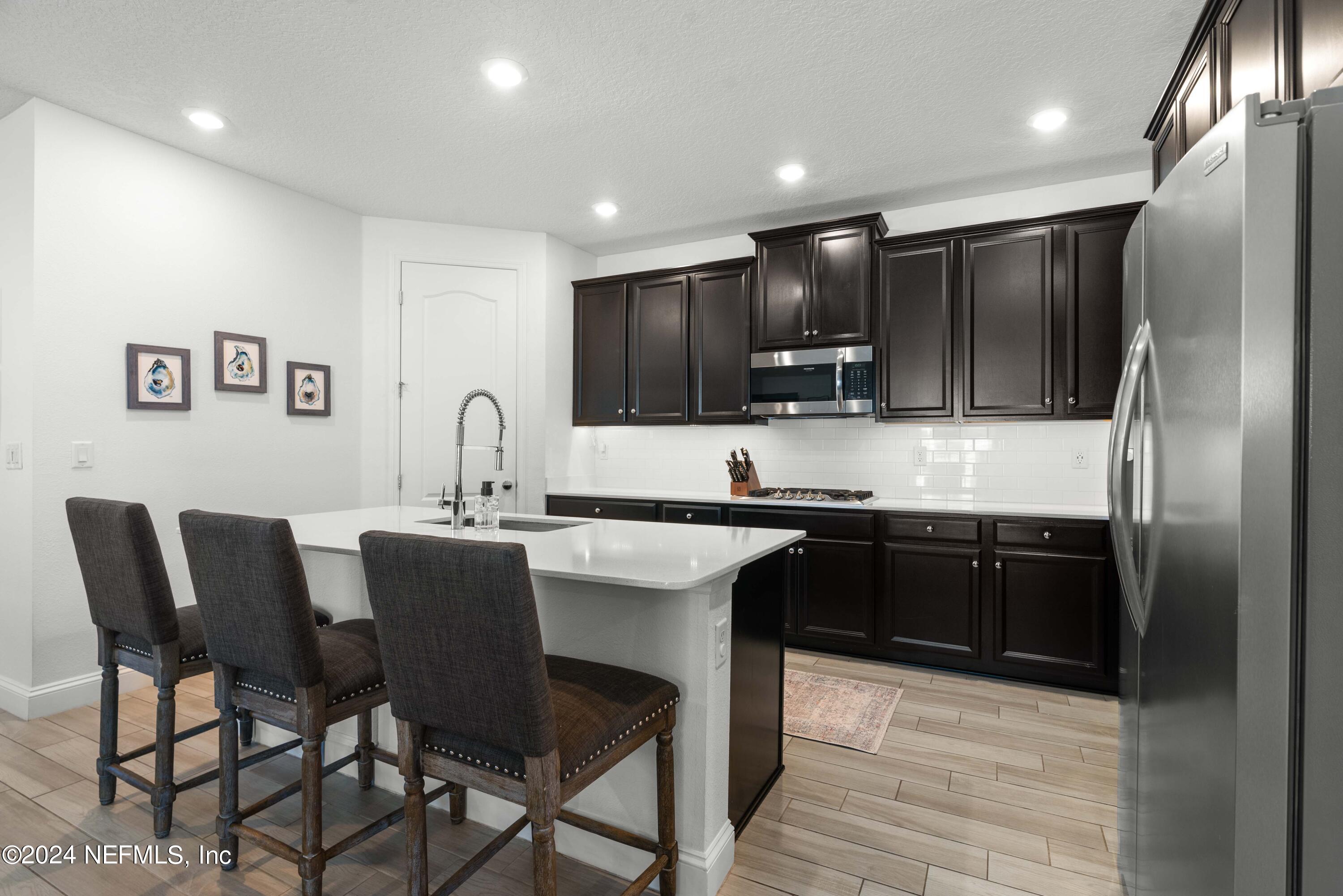 2672 Alexia Circle Jacksonville, FL 32246 - Photo 5 of 33 a kitchen with stainless steel appliances granite countertop a sink a stove a microwave a dining table and chairs