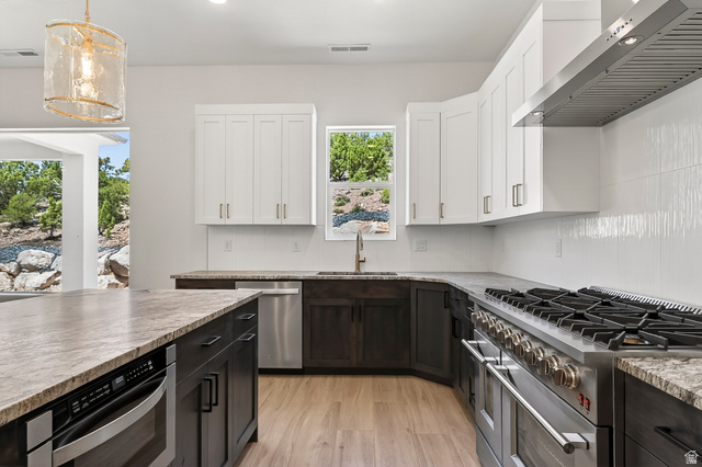 2862 South Mountain Rnch Road Cedar City, UT 84720 - Photo 15 of 64 Modern kitchen featuring light wood-finish flooring, two-tone cabinetry with dark lower cabinets and white upper cabinets, and a granite-finish countertop